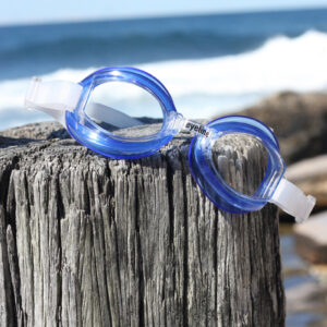 a pair of blue aqua mate swim goggles sitting on a wooden post at the beach